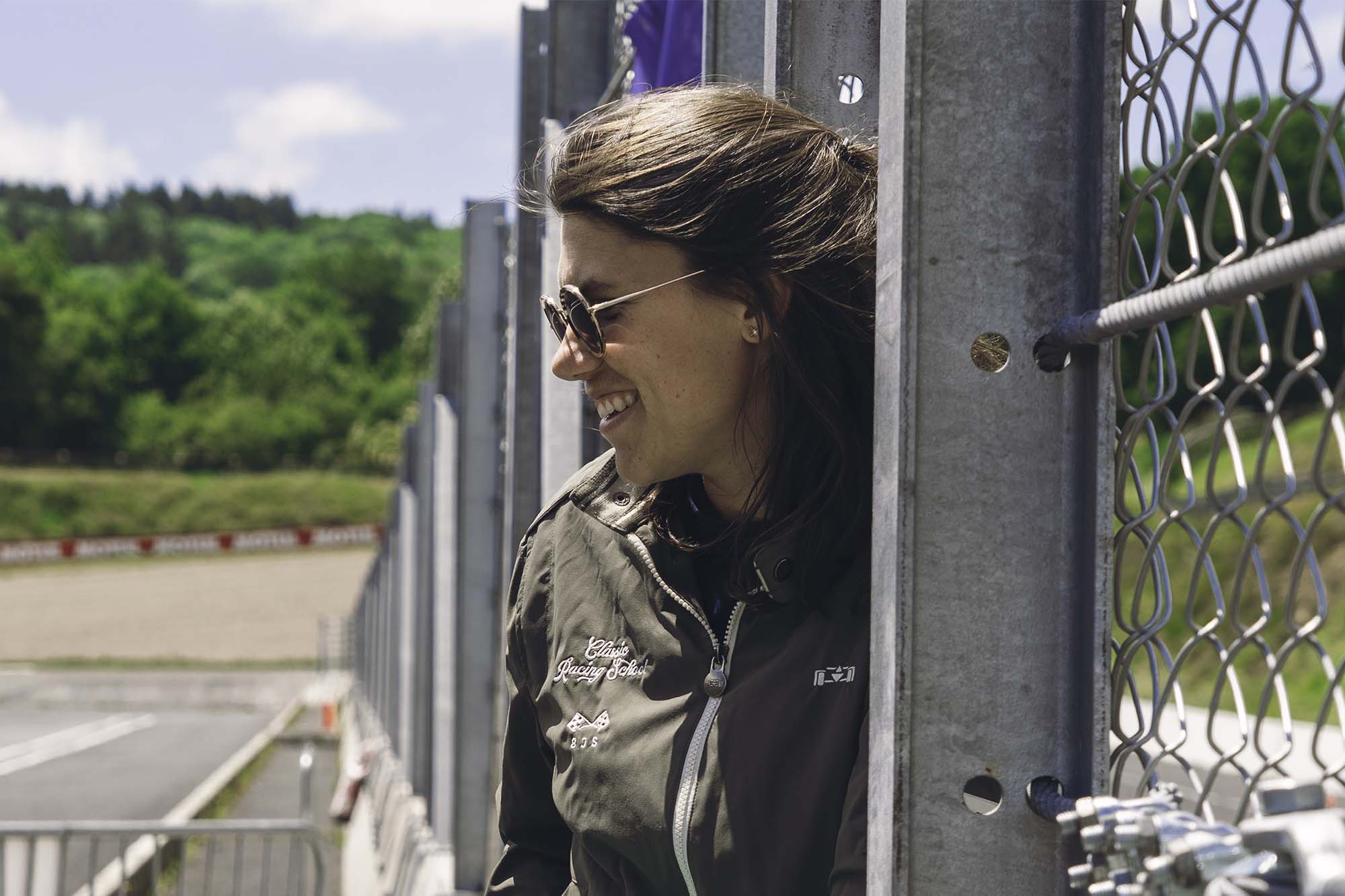 une femme appuyée contre une clôture métallique. L'équipe