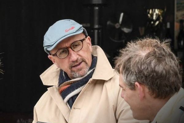 un homme avec un chapeau bleu et un trench-coat. L'équipe