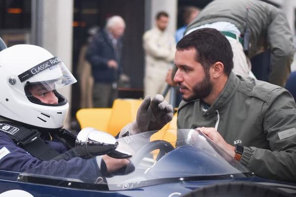 un homme portant un casque parlant à un autre homme dans une voiture de course. L'équipe